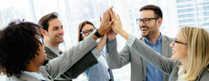 Business team members giving a group high five during a meeting to celebrate collaboration, teamwork, and workplace success.