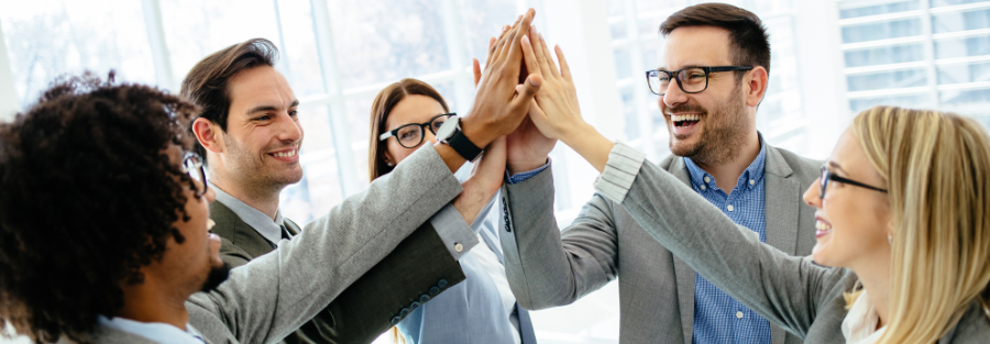 Business team members giving a group high five during a meeting to celebrate collaboration, teamwork, and workplace success.