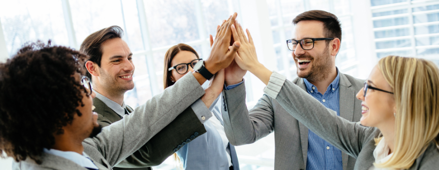 Business team members giving a group high five during a meeting to celebrate collaboration, teamwork, and workplace success.